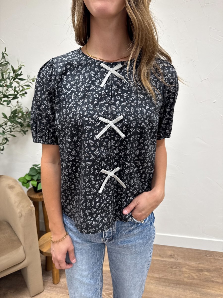 Front view of model wearing bow detail floral blouse with tie neck design — Three:Twelve Boutique