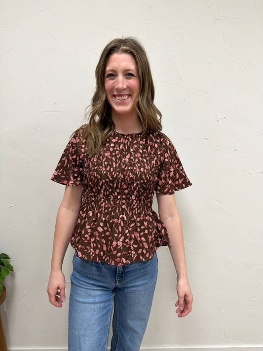 Front view of model wearing floral smocked peplum blouse showing fitted bodice — Three:Twelve Boutique