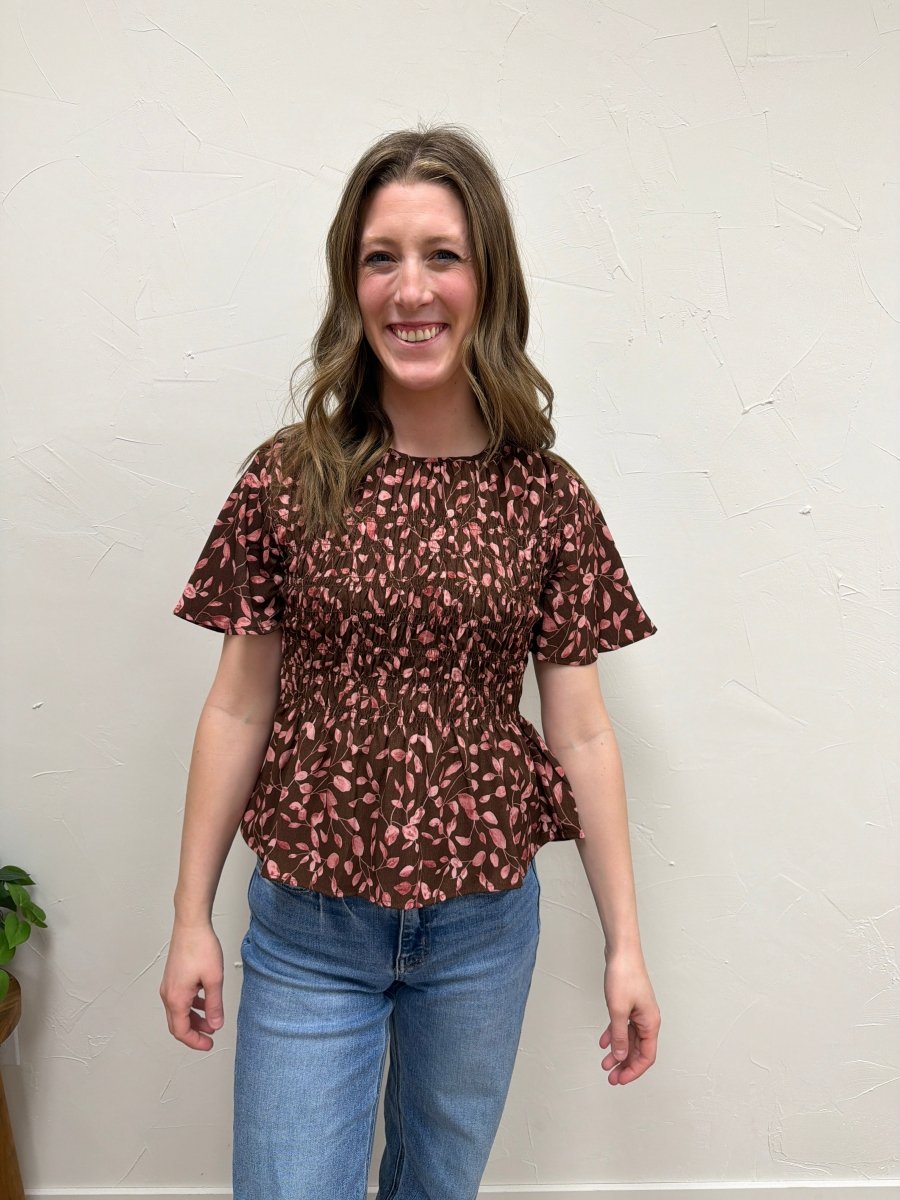 Front view of model wearing floral smocked peplum blouse showing fitted bodice — Three:Twelve Boutique
