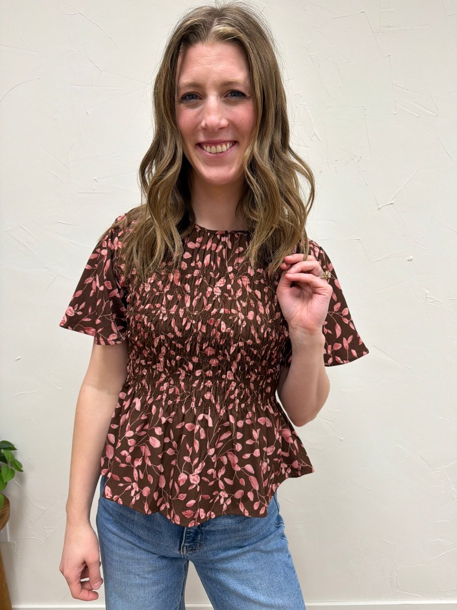 Front view of model wearing floral smocked peplum blouse showing fitted bodice — Three:Twelve Boutique