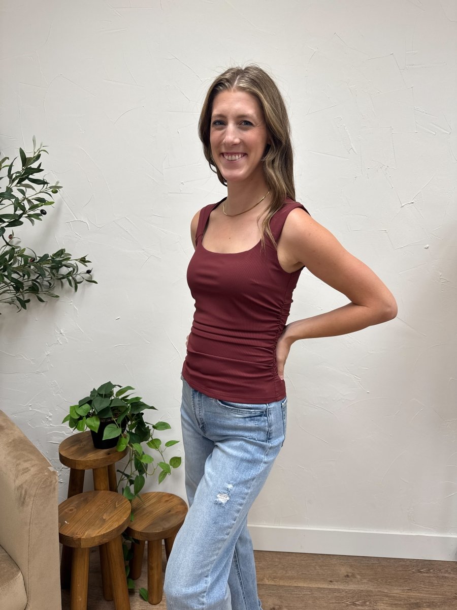 Lifestyle shot of model wearing burgundy sleeveless ruched knit top with denim — Three:Twelve Boutique