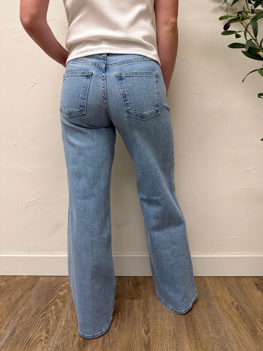 Back view of model wearing denim jeans highlighting pockets and wide-leg silhouette — Three:Twelve Boutique
